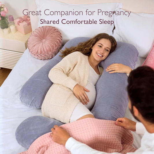 Woman using a U-shaped pregnancy pillow with a partner in a bedroom setting.