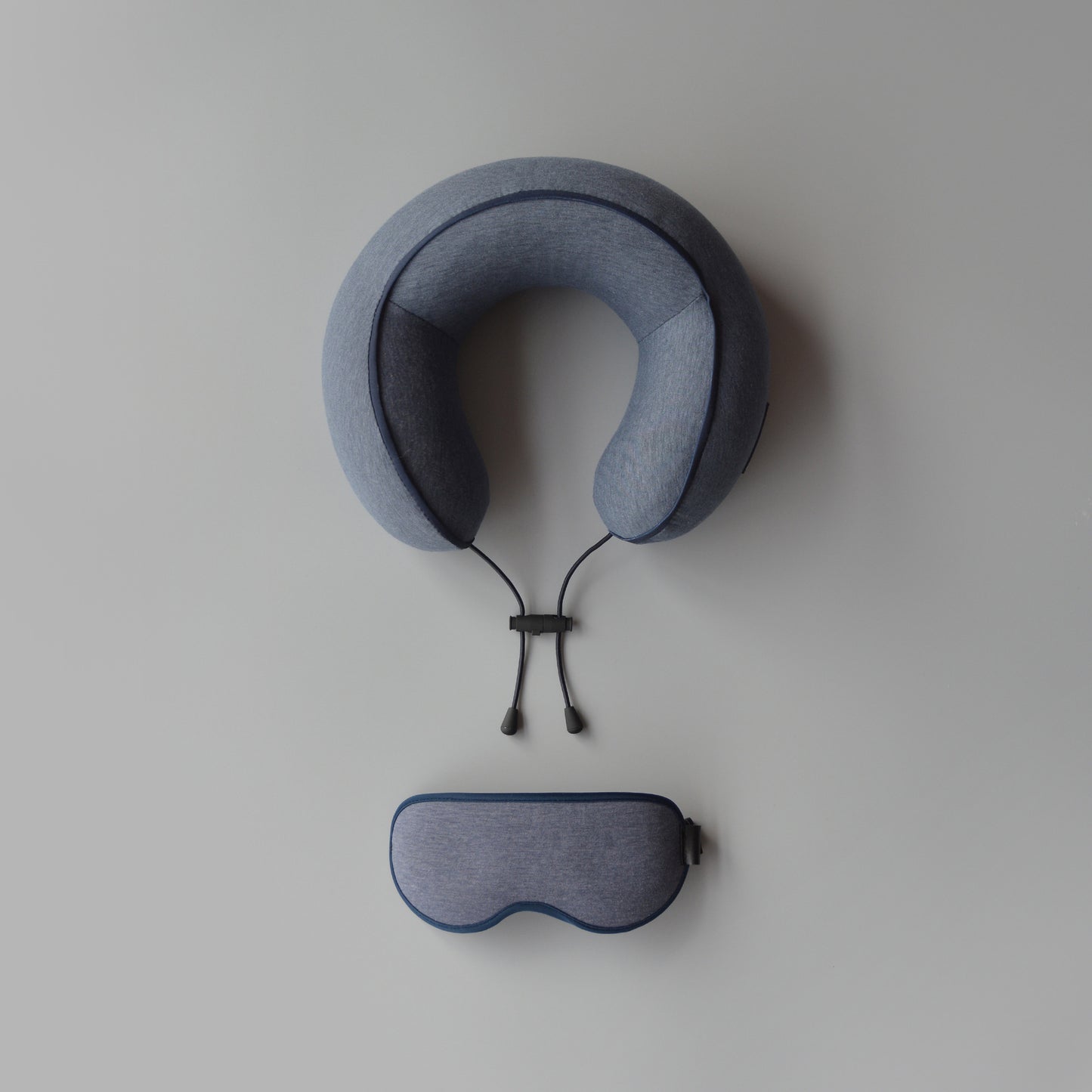 Blue travel pillow and eye mask on a light gray background
