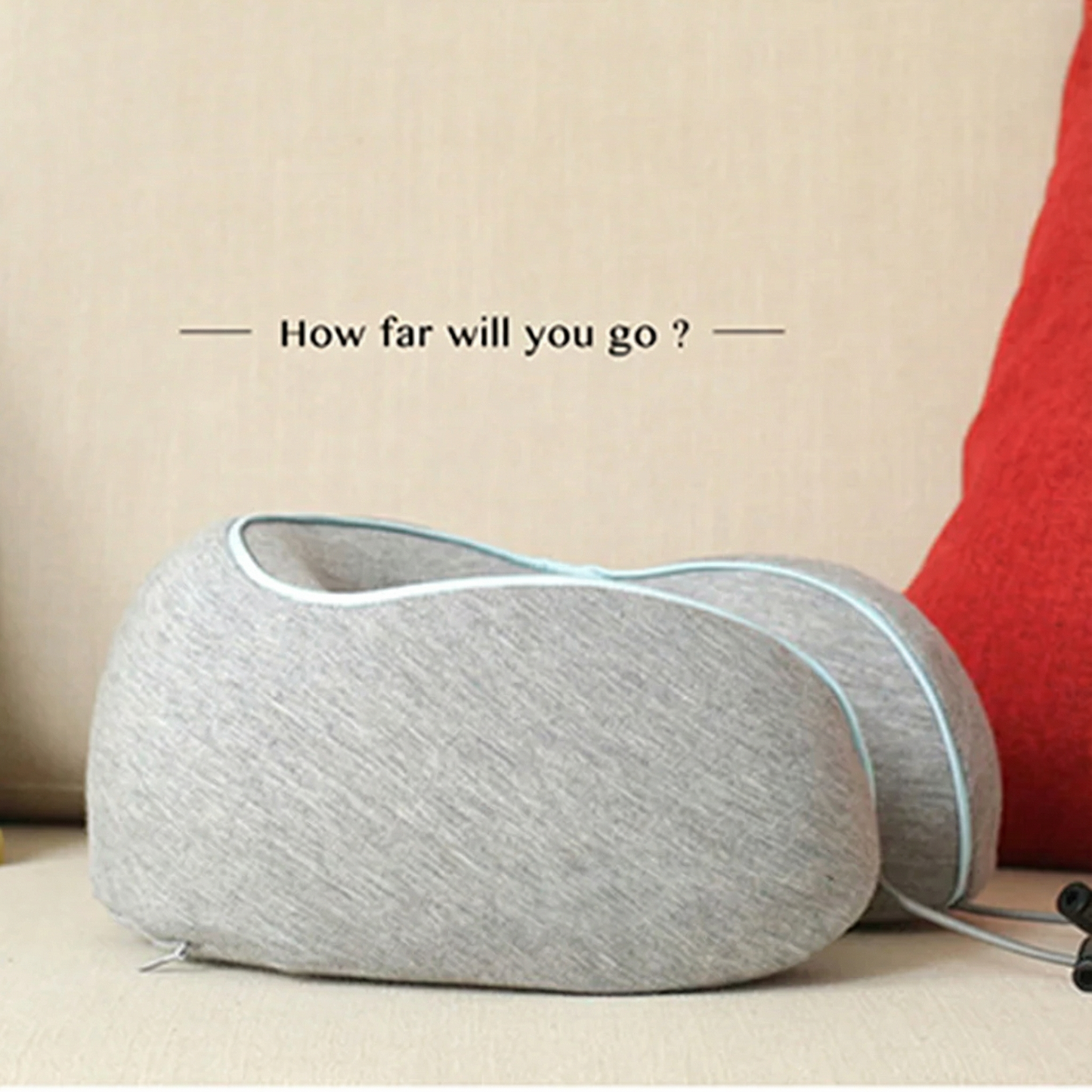 Gray travel pillow on a beige surface with text 'How far will you go?'