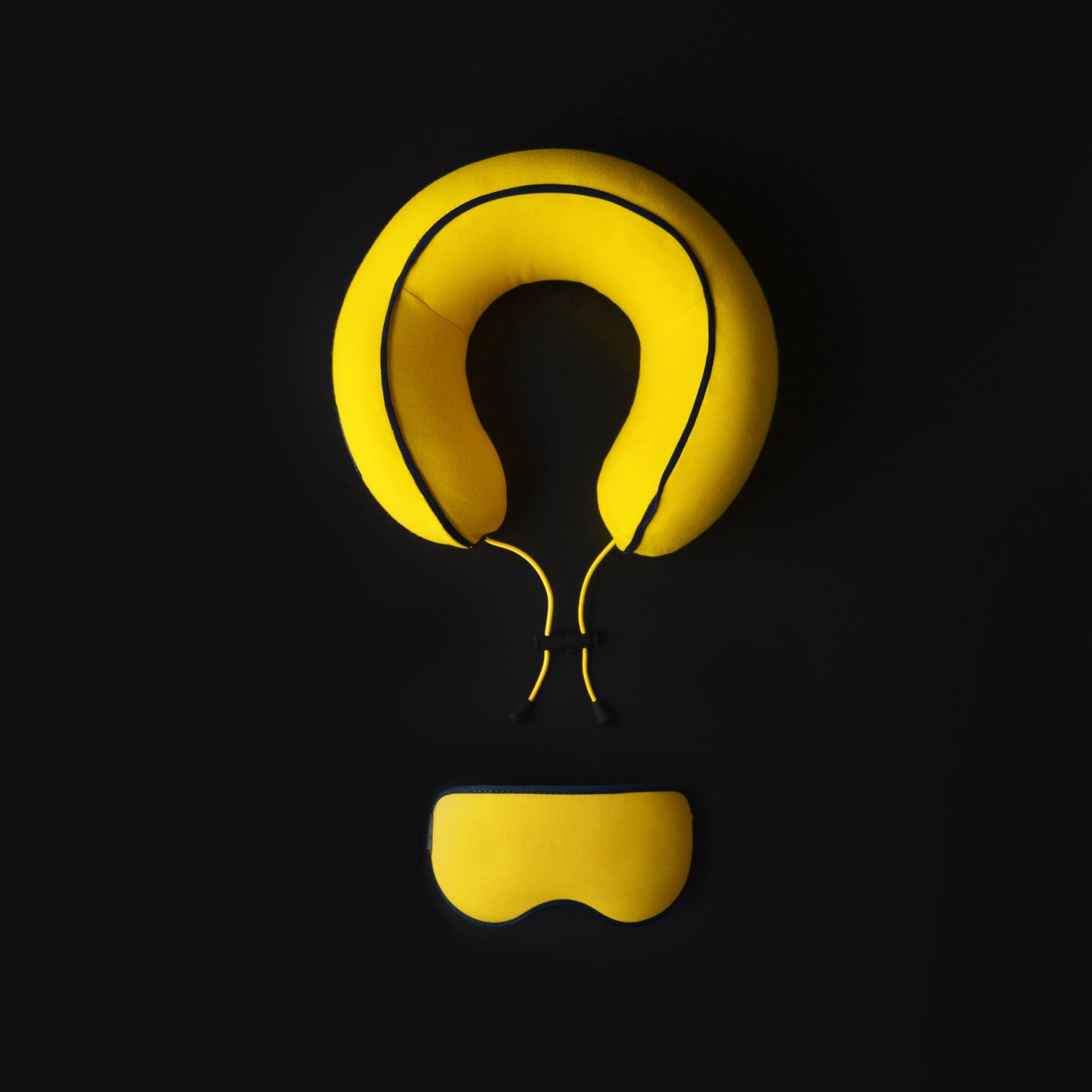 Yellow Neck pillow and eye mask set on a dark background